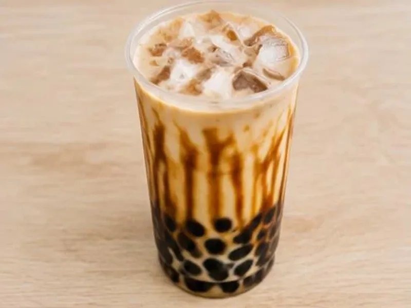 Cup of brown sugar boba milk with tapioca pearls on a wooden table