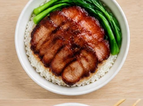 Plate of char siu roast pork over rice on a wooden table