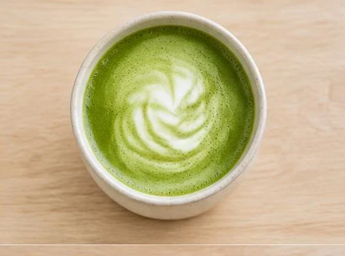 Cup of green matcha latte on a wooden table