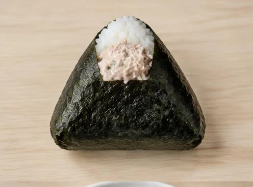 Tuna mayo onigiri rice triangle wrapped in nori on a wooden board