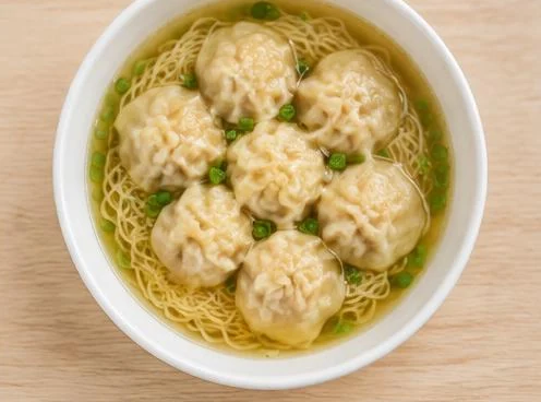 Bowl of wonton noodle soup with dumplings on a wooden table
